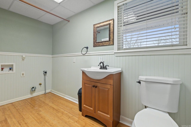 bathroom with hardwood / wood-style flooring, vanity, toilet, and a drop ceiling