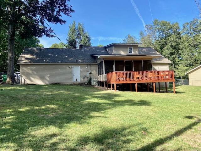 rear view of house featuring a sunroom, a deck, and a lawn