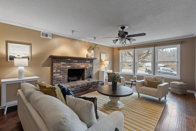 living room with dark hardwood / wood-style floors, ornamental molding, ceiling fan, a brick fireplace, and a textured ceiling