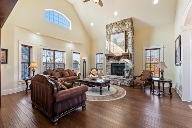 living room featuring a stone fireplace, high vaulted ceiling, dark hardwood / wood-style floors, and ceiling fan