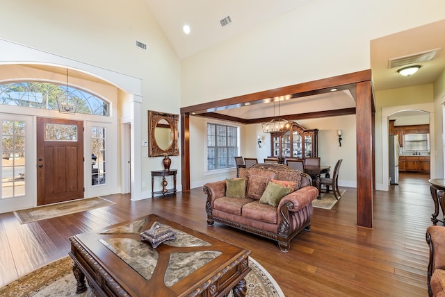 living room with dark wood-type flooring, a chandelier, and high vaulted ceiling