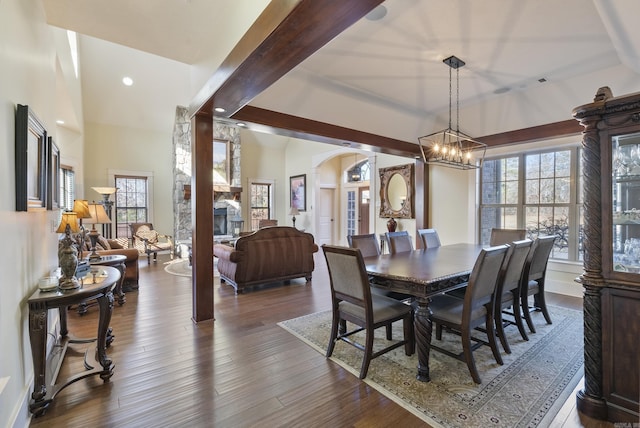 dining space with a chandelier, a healthy amount of sunlight, beam ceiling, and dark hardwood / wood-style flooring