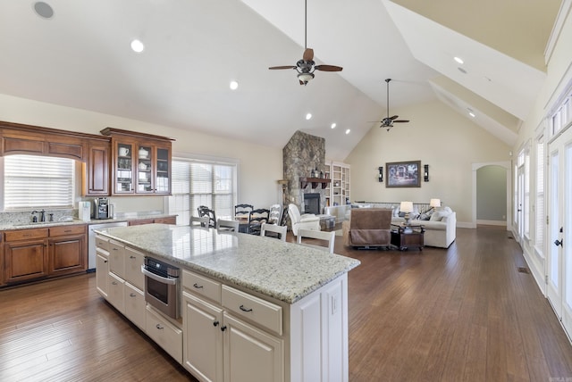 kitchen featuring stainless steel appliances, a fireplace, light stone countertops, and a kitchen island