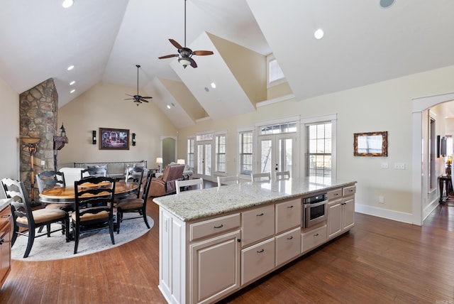 kitchen featuring oven, a center island, light stone countertops, dark wood-type flooring, and french doors