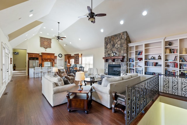 living room with ceiling fan, a stone fireplace, high vaulted ceiling, and dark hardwood / wood-style flooring