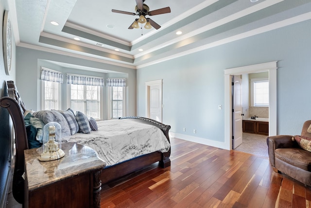 bedroom featuring ensuite bathroom, crown molding, a tray ceiling, ceiling fan, and hardwood / wood-style floors