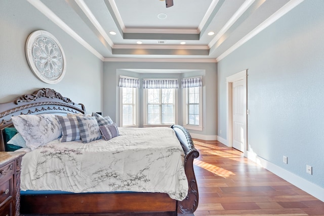 bedroom with a tray ceiling, ornamental molding, and hardwood / wood-style flooring