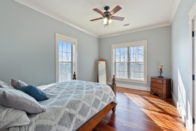 bedroom with ceiling fan, wood-type flooring, multiple windows, and ornamental molding