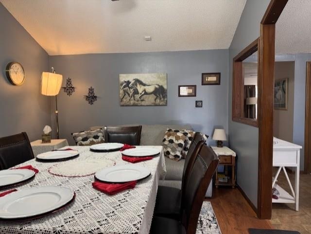 dining room with hardwood / wood-style flooring, lofted ceiling, and a textured ceiling