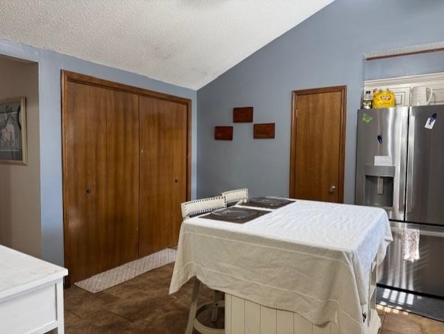 bedroom with stainless steel fridge, a closet, a textured ceiling, and vaulted ceiling