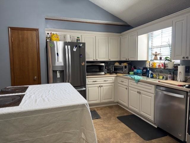 kitchen with white cabinetry, appliances with stainless steel finishes, and lofted ceiling