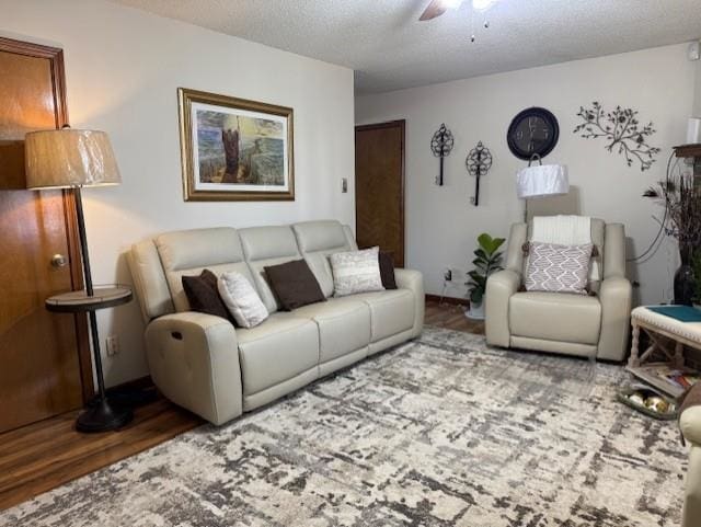 living room with ceiling fan, wood-type flooring, and a textured ceiling