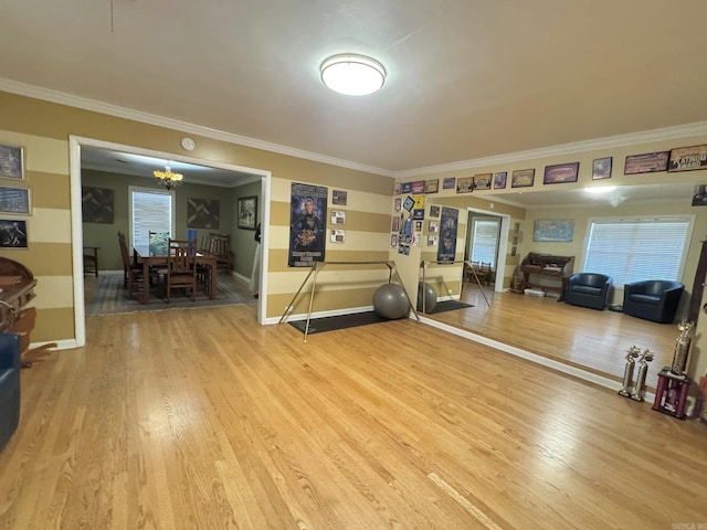 workout room with wood-type flooring, ornamental molding, and an inviting chandelier