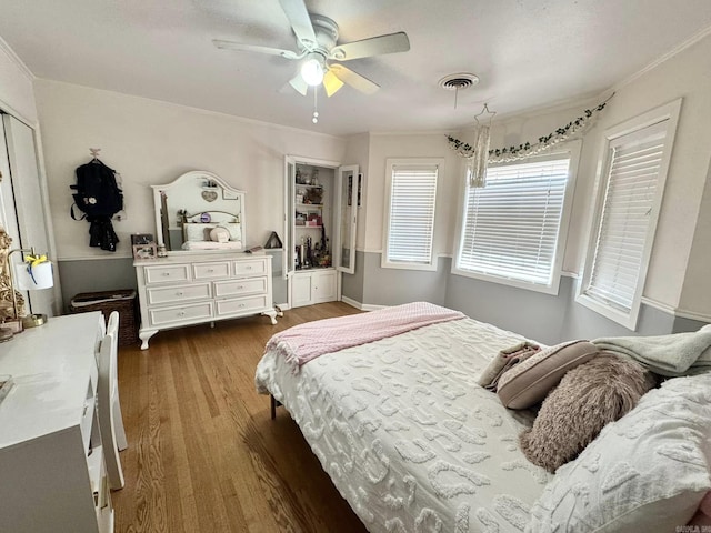 bedroom featuring dark wood-type flooring, ceiling fan, and ornamental molding