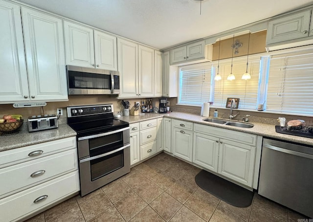 kitchen featuring sink, decorative light fixtures, light tile patterned floors, and appliances with stainless steel finishes