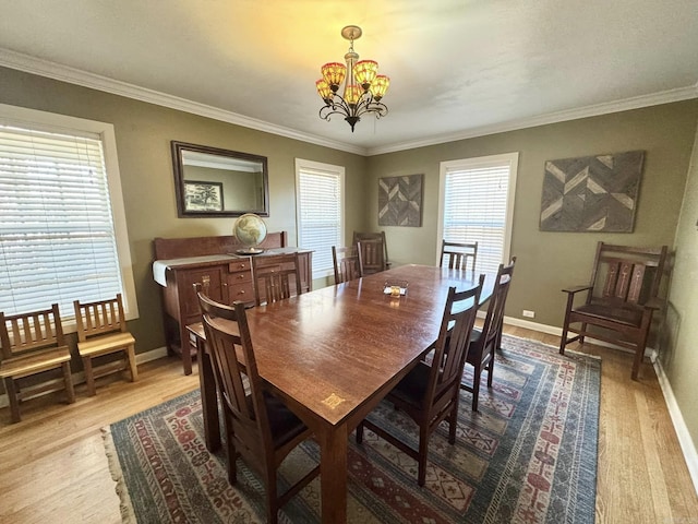 dining space featuring crown molding, an inviting chandelier, and light hardwood / wood-style floors