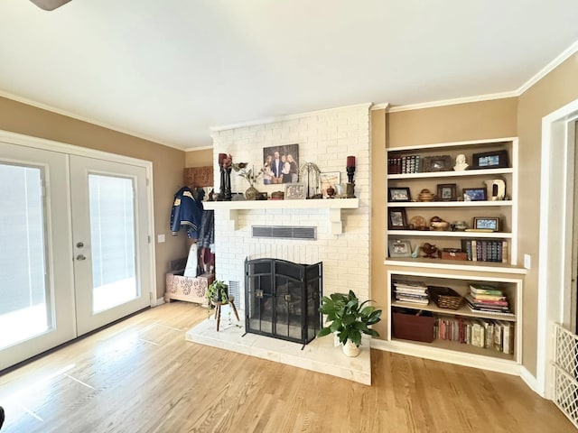 living room with wood-type flooring, a brick fireplace, and french doors