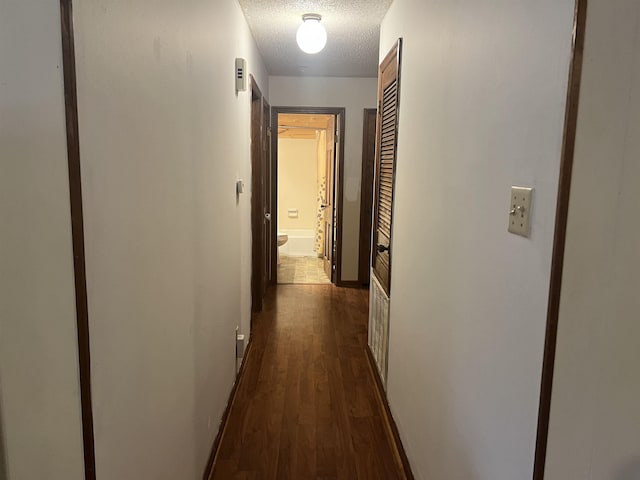 hall with dark hardwood / wood-style flooring and a textured ceiling