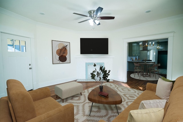 living room featuring ceiling fan with notable chandelier, wood-type flooring, and ornamental molding