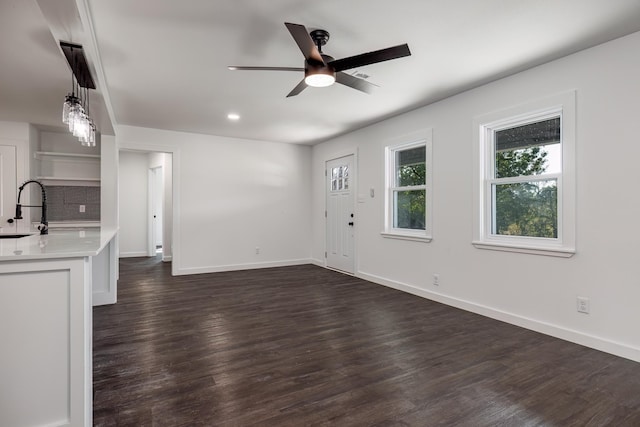 unfurnished living room featuring sink, dark wood-type flooring, and ceiling fan