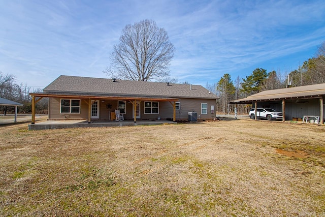 back of property with a carport, central AC unit, and a lawn