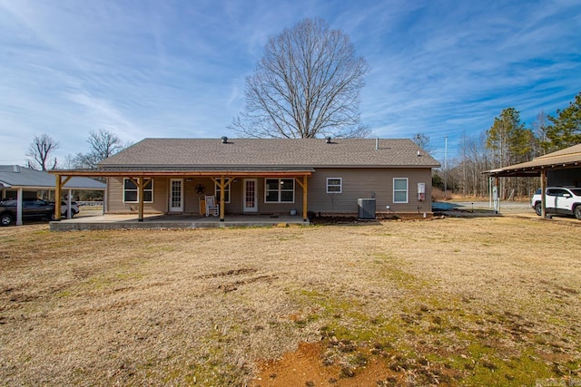 rear view of property featuring central AC, a carport, a patio area, and a lawn