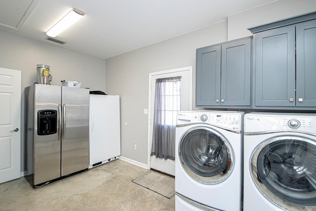 clothes washing area featuring cabinets and independent washer and dryer