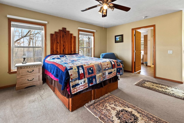 carpeted bedroom with a textured ceiling, ceiling fan, and ensuite bath