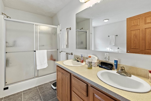 bathroom with a shower with door, vanity, and tile patterned flooring