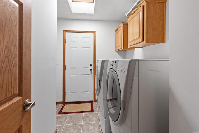 washroom with cabinets, light tile patterned floors, washer and clothes dryer, and a skylight