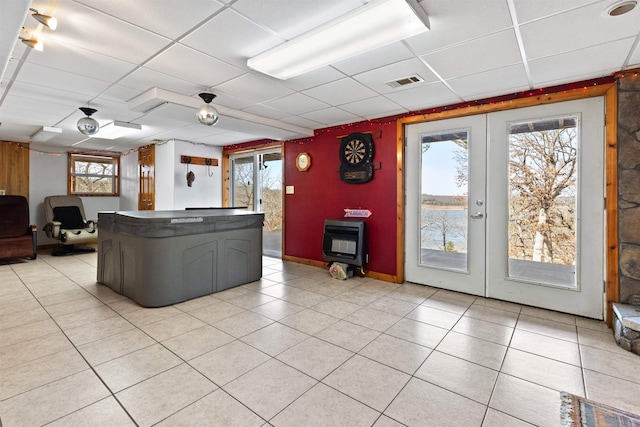 unfurnished living room featuring a paneled ceiling, heating unit, light tile patterned floors, and french doors