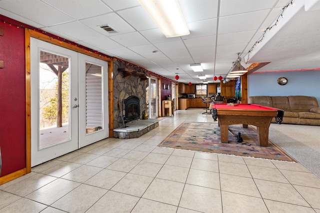 playroom featuring french doors, pool table, a stone fireplace, and light tile patterned floors