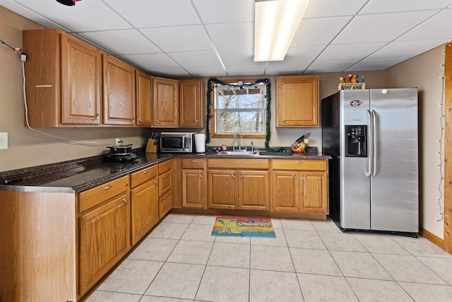 kitchen with light tile patterned flooring, appliances with stainless steel finishes, sink, and a drop ceiling