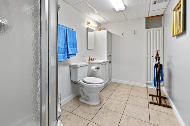 bathroom featuring toilet, vanity, a shower with door, tile patterned flooring, and a drop ceiling