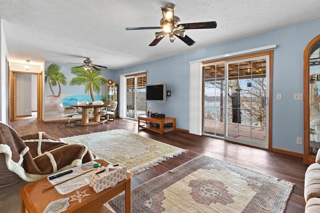 living room featuring ceiling fan, dark hardwood / wood-style floors, and a textured ceiling