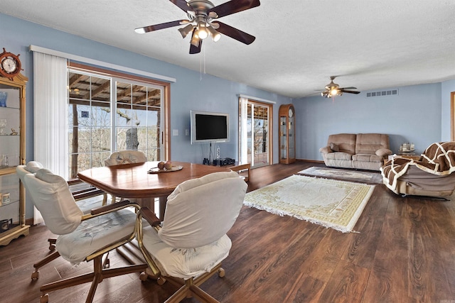 dining area with ceiling fan, dark wood-type flooring, and a textured ceiling