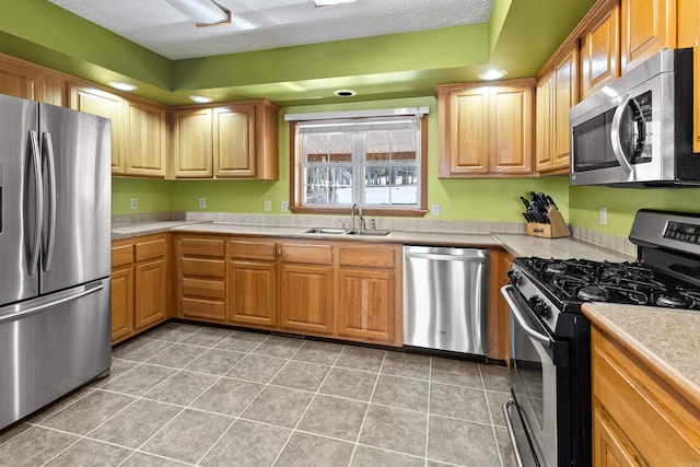 kitchen with stainless steel appliances, sink, a textured ceiling, and light tile patterned floors