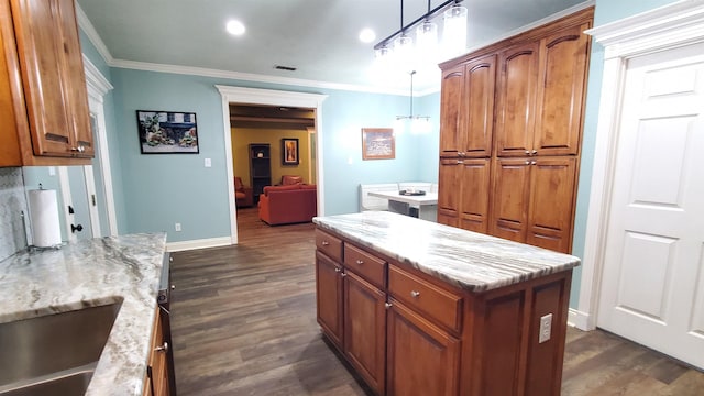 kitchen featuring light stone counters, decorative light fixtures, ornamental molding, dark hardwood / wood-style floors, and a kitchen island