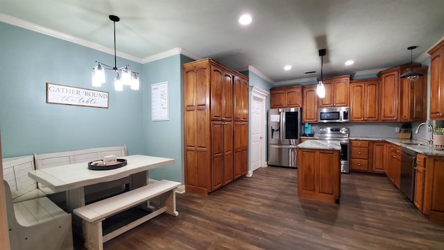 kitchen with a kitchen island, pendant lighting, sink, stainless steel appliances, and light stone countertops