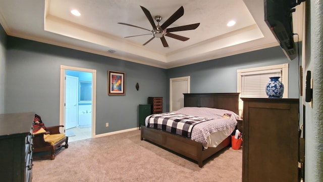 bedroom with a tray ceiling, ensuite bath, and ceiling fan