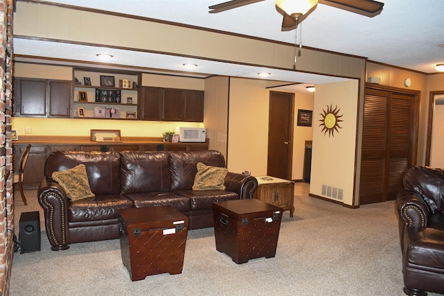 carpeted living room featuring ceiling fan and ornamental molding