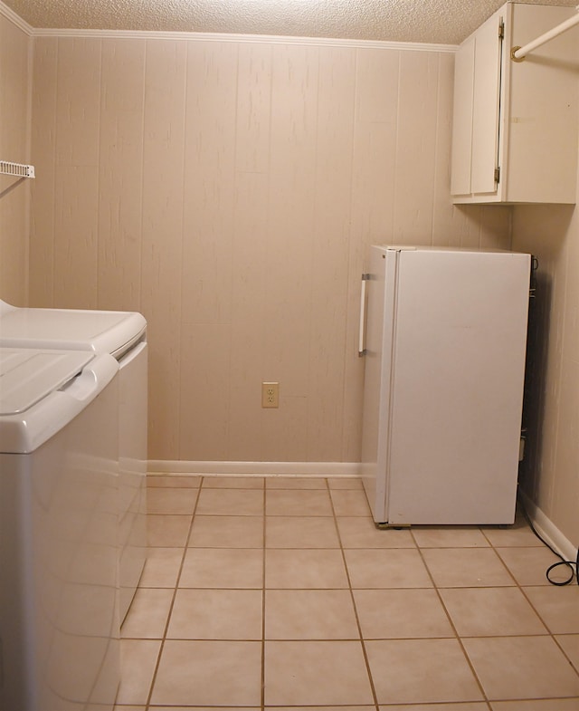 washroom with cabinets, wooden walls, washing machine and dryer, and light tile patterned floors