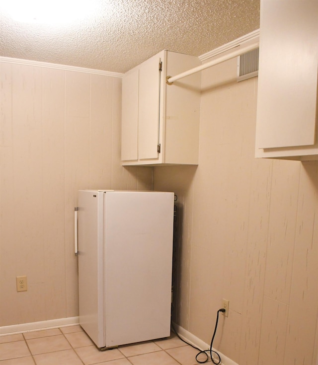 clothes washing area featuring wooden walls, a textured ceiling, and light tile patterned floors