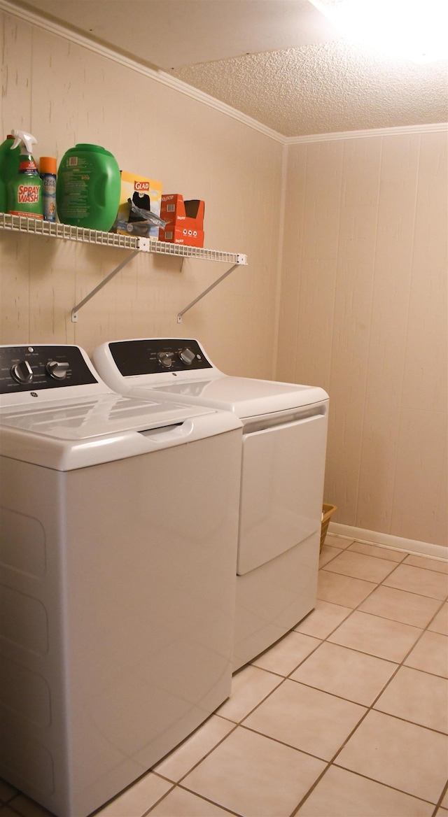 washroom with wooden walls, separate washer and dryer, and light tile patterned floors