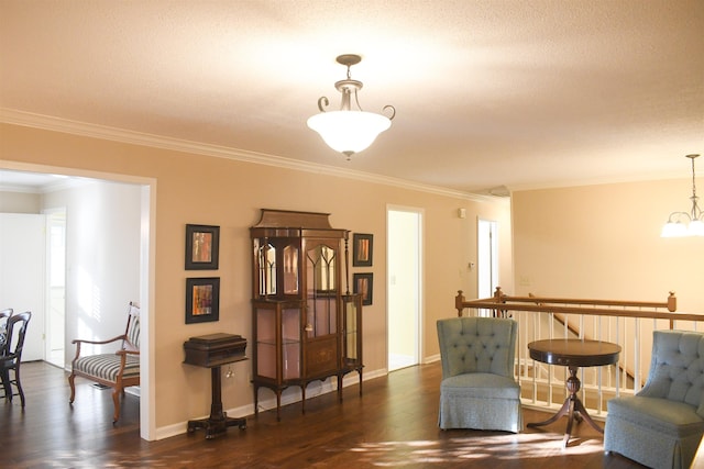 sitting room with dark wood-type flooring, ornamental molding, and a chandelier