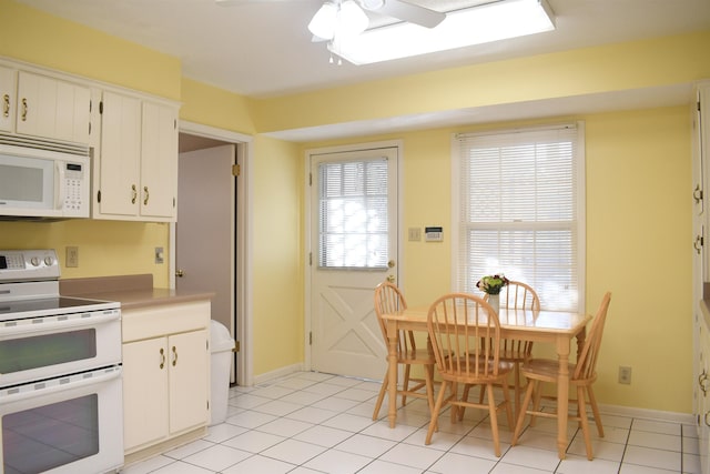 kitchen with light tile patterned flooring, white appliances, ceiling fan, and white cabinets