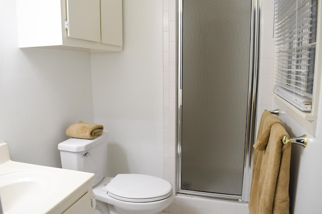 bathroom with vanity, a shower with door, and toilet