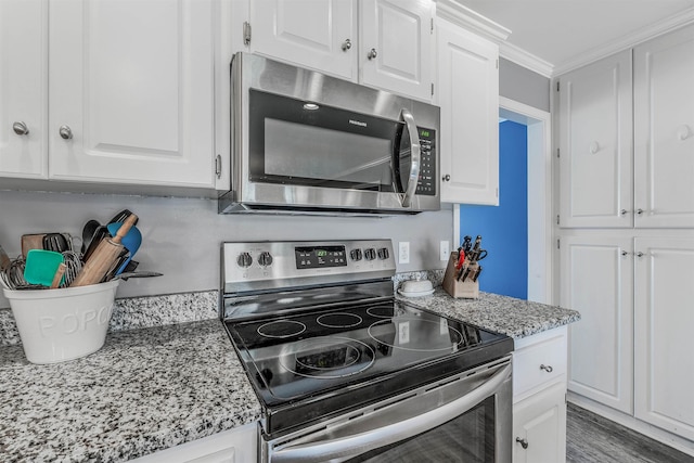 kitchen featuring crown molding, appliances with stainless steel finishes, light stone countertops, hardwood / wood-style floors, and white cabinets