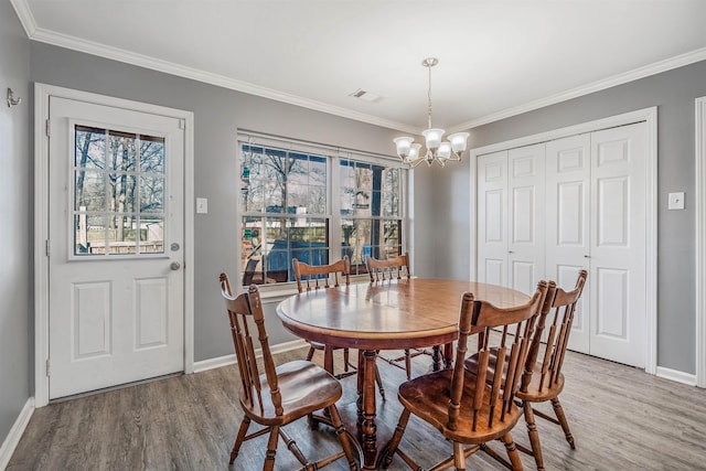 dining space with hardwood / wood-style floors, crown molding, and a chandelier