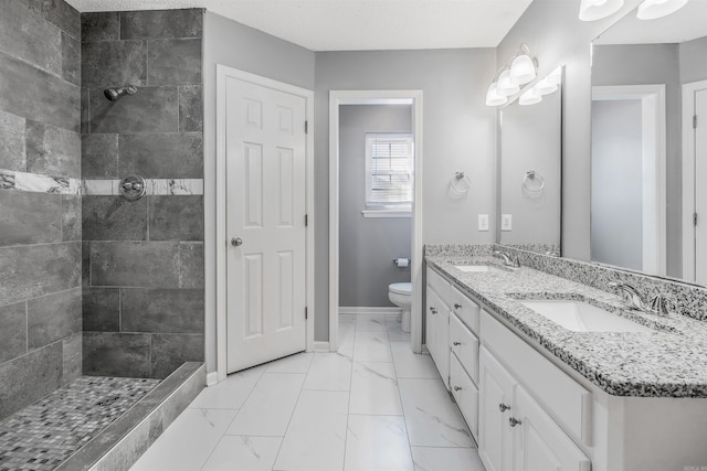 bathroom with vanity, a textured ceiling, toilet, and tiled shower